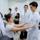 Estudantes de Fisioterapia da Unoeste em aula prática, avaliando movimentos do braço de uma colega sob supervisão de professor, em ambiente de laboratório.