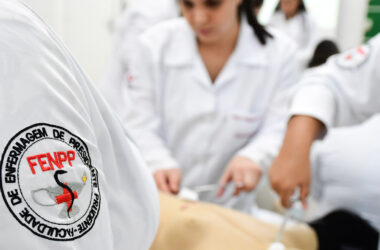 Estudantes da Faculdade de Enfermagem da Unoeste em aula prática com jaleco branco e símbolo institucional bordado no uniforme, representando o cuidado, a formação técnica e o compromisso com a Enfermagem.