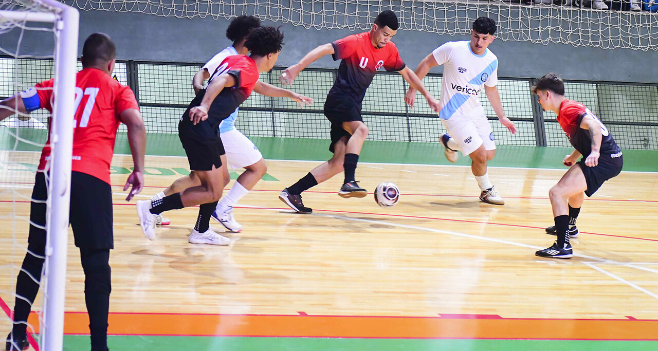 Jogo de futsal em quadra com jogadores disputando a bola em ritmo intenso, representando o foco, a velocidade e a superação presentes nos filmes esportivos.