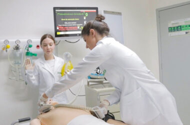 Alunas de Medicina da Unoeste realizam treinamento prático em um laboratório de simulação realística, utilizando manequim de alta fidelidade, desfibrilador e monitor cardíaco durante exercício de atendimento de emergência.