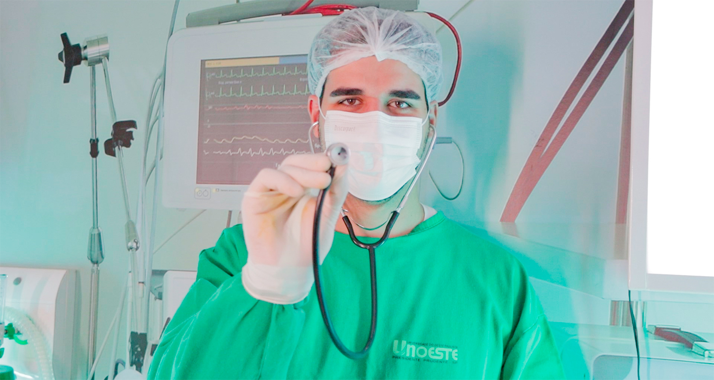 Estudante de Medicina com jaleco cirúrgico e estetoscópio em ambiente hospitalar, simbolizando a prática médica e o cuidado com a saúde.