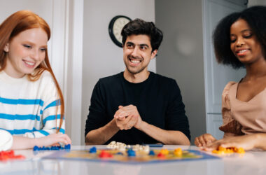 Grupo de jovens adultos interagindo em uma atividade com jogo de tabuleiro, estimulando habilidades cognitivas como atenção, raciocínio e socialização em ambiente colaborativo.