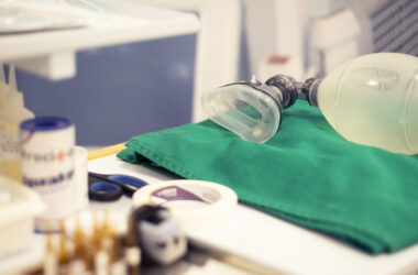 Equipamentos de anestesia organizados em bancada hospitalar, com máscara e ambu sobre campo cirúrgico verde, utilizados em procedimentos anestésicos e cirúrgicos.