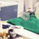 Equipamentos de anestesia organizados em bancada hospitalar, com máscara e ambu sobre campo cirúrgico verde, utilizados em procedimentos anestésicos e cirúrgicos.