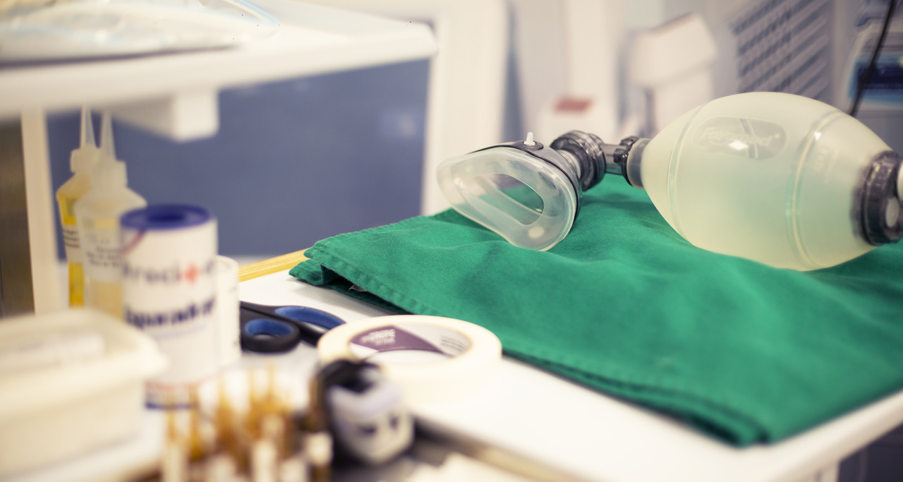 Equipamentos de anestesia organizados em bancada hospitalar, com máscara e ambu sobre campo cirúrgico verde, utilizados em procedimentos anestésicos e cirúrgicos.