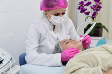 Aluna do curso de Estética e Cosmética realiza procedimento facial com equipamento estético em clínica-escola, durante aula prática supervisionada.