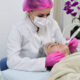 Aluna do curso de Estética e Cosmética realiza procedimento facial com equipamento estético em clínica-escola, durante aula prática supervisionada.