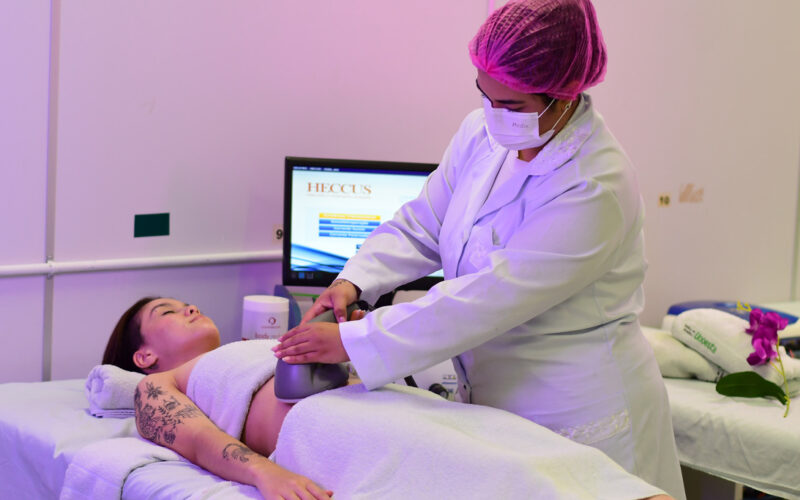 Estudante de Estética e Cosmética da Unoeste realiza procedimento corporal com equipamento em paciente, em clínica-escola da Unoeste, durante aula prática supervisionada.