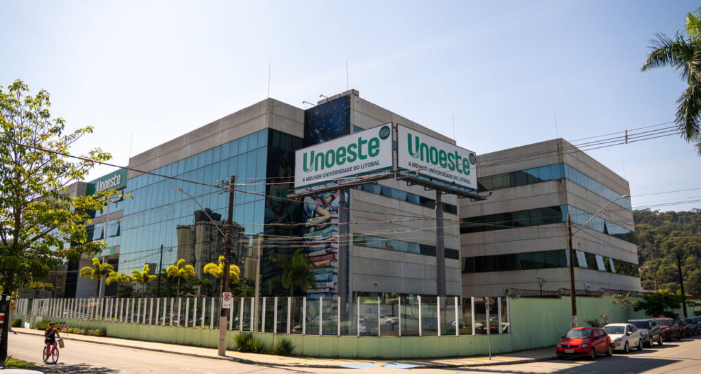 Prédio da Unoeste no Guarujá com fachada moderna em vidro e logotipo institucional em destaque.