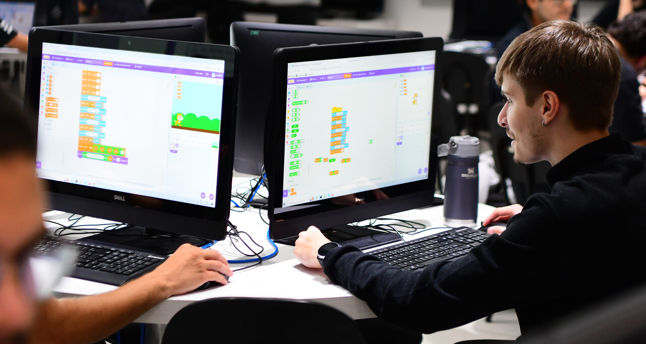 Estudantes de Sistemas de Informação da Unoeste em laboratório de informática, utilizando computadores para desenvolver e testar sistemas e aplicações digitais durante atividade prática.