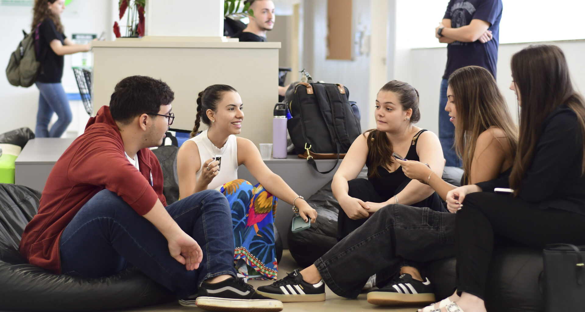 Estudantes universitários reunidos em grupo conversam e trocam ideias em ambiente acadêmico, representando colaboração e empreendedorismo na faculdade.