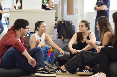 Estudantes universitários reunidos em grupo conversam e trocam ideias em ambiente acadêmico, representando colaboração e empreendedorismo na faculdade.