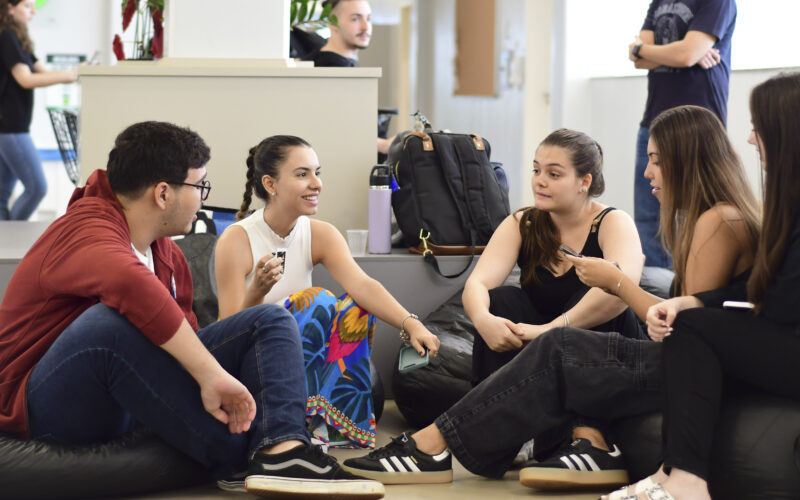 Estudantes universitários reunidos em grupo conversam e trocam ideias em ambiente acadêmico, representando colaboração e empreendedorismo na faculdade.