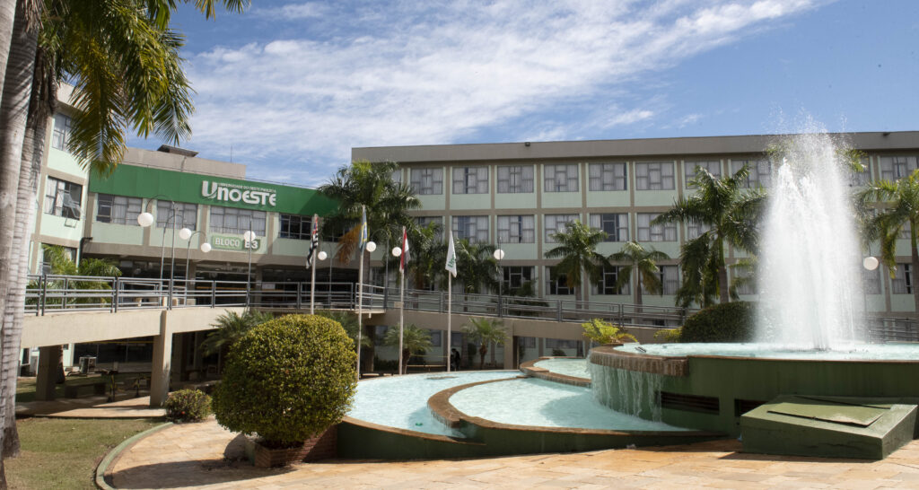 Área interna do campus 2 da Unoeste em Presidente Prudente com prédio acadêmico, fonte central e espaços de convivência ao ar livre.