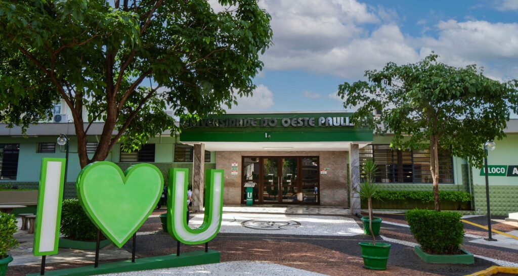 Entrada do campus 1 da Unoeste em Presidente Prudente com escultura “I love U”, área arborizada e fachada da universidade ao fundo