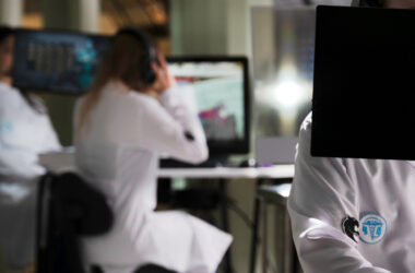 Estudantes de Medicina utilizando computadores e tecnologia digital em ambiente de simulação, demonstrando o uso de recursos tecnológicos e jogos aplicados ao aprendizado médico.