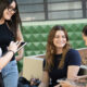 Grupo de estudantes conversando e estudando ao ar livre no campus universitário, utilizando tablets e materiais digitais durante a preparação para o Enem.