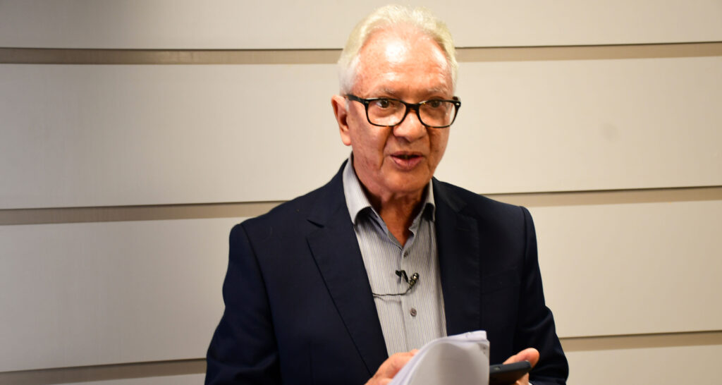 Médico infectologista, mestre e doutor em imunologia e docente da Unoeste, Dr. Luiz Euribel Prestes Carneiro, durante entrevista em ambiente interno, segurando anotações e utilizando microfone de lapela.