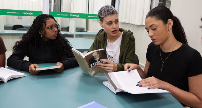Estudantes reunidas em sala de estudos da Unoeste, lendo livros e debatendo conteúdos relacionados à Psicologia e comportamento humano.