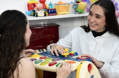 Estudante de Terapia Ocupacional da Unoeste realiza atividade prática utilizando brinquedo educativo em atendimento simulado. A cena ocorre em um ambiente terapêutico com brinquedos, materiais lúdicos e recursos utilizados no desenvolvimento de habilidades cognitivas, motoras e sensoriais.