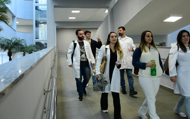 Estudantes de Medicina caminham pelos corredores do campus da Unoeste durante a rotina acadêmica, em ambiente moderno e amplo, que integra espaços de convivência e aprendizagem para a formação médica.