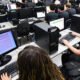 Estudantes utilizam computadores durante aula prática de programação em laboratório de informática, aprendendo linguagens de programação.