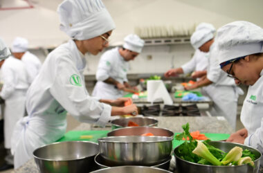 Estudantes da faculdade de Gastronomia da Unoeste participam de uma aula prática em laboratório de cozinha, preparando ingredientes, utilizando utensílios profissionais e desenvolvendo técnicas culinárias essenciais para a formação de futuros chefs de cozinha e personal chefs.