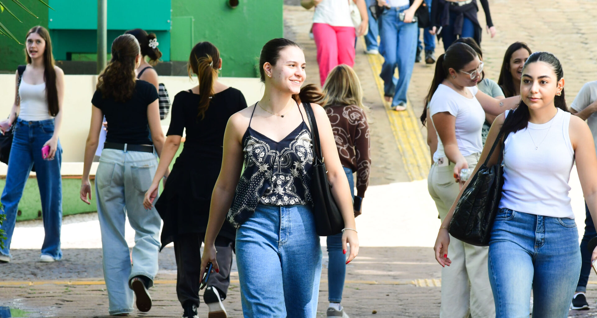 Alunos circulam pelo campus da Unoeste durante o intervalo das aulas, carregando mochilas e bolsas em um ambiente universitário.