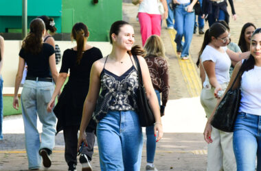 Alunos circulam pelo campus da Unoeste durante o intervalo das aulas, carregando mochilas e bolsas em um ambiente universitário.