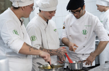 Estudantes de Gastronomia da Unoeste preparam receitas durante aula prática em cozinha profissional, acompanhando técnicas de preparo dos alimentos.