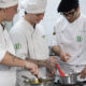 Estudantes de Gastronomia da Unoeste preparam receitas durante aula prática em cozinha profissional, acompanhando técnicas de preparo dos alimentos.