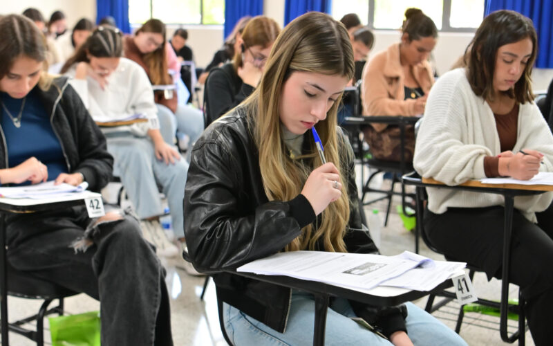 Candidatos concentrados realizam prova de vestibular da Unoeste em sala de aula, sentados individualmente em carteiras e respondendo às questões impressas.