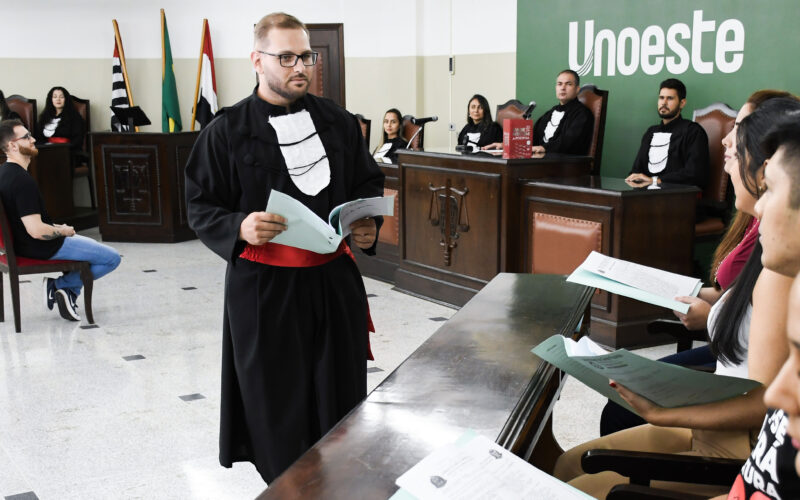 Estudantes do curso de Direito participam de atividade prática em tribunal simulado da Unoeste, com apresentação diante da bancada de julgamento.