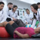 Estudantes de Fisioterapia realizam atendimento prático com pacientes em laboratório, utilizando bola terapêutica durante exercícios de reabilitação.