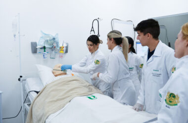 Estudantes de Enfermagem da Unoeste participam de atividade prática em laboratório de simulação, realizando procedimentos em um manequim hospitalar.