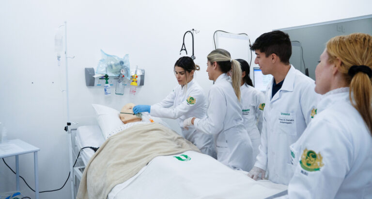 Estudantes de Enfermagem da Unoeste participam de atividade prática em laboratório de simulação, realizando procedimentos em um manequim hospitalar.