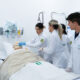 Estudantes de Enfermagem da Unoeste participam de atividade prática em laboratório de simulação, realizando procedimentos em um manequim hospitalar.