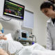 Estudante de Enfermagem da Unoeste realiza atividade prática em laboratório de simulação, ao lado de manequim hospitalar conectado a equipamentos de monitoramento.