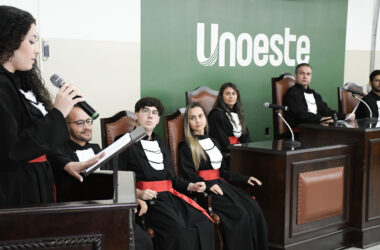 Estudantes do curso de Direito da Unoeste participam de atividade prática em tribunal simulado, com apresentação oral diante de uma bancada.