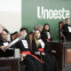 Estudantes do curso de Direito da Unoeste participam de atividade prática em tribunal simulado, com apresentação oral diante de uma bancada.