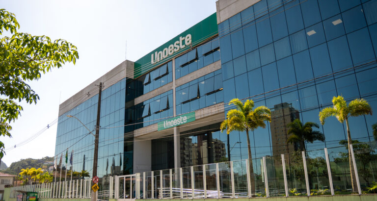 Fachada do campus da Unoeste no Guarujá, com entrada principal, palmeiras e identificação da universidade no prédio.