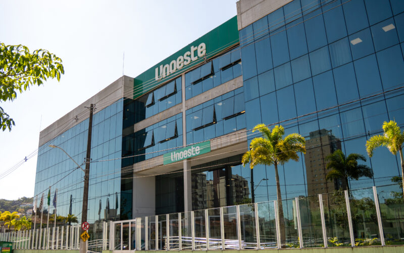 Fachada do campus da Unoeste no Guarujá, com entrada principal, palmeiras e identificação da universidade no prédio.
