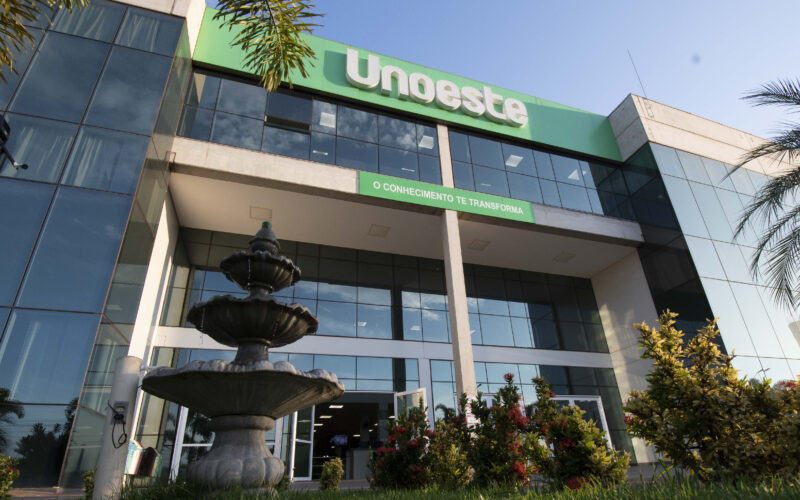 Fachada do campus da Unoeste em Jaú, com entrada principal, fonte e jardins em frente ao prédio da universidade.