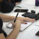 Estudante faz anotações em caderno durante atividade em sala de aula, com materiais da Unoeste sobre a mesa.